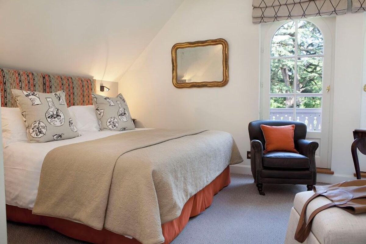 A bedroom with a bed, a chair, a mirror, and a window.