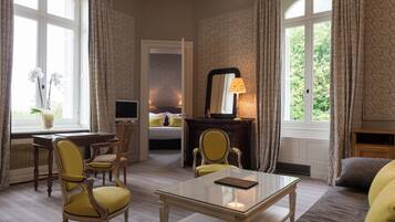 A hotel room with a bed, a desk, a chair, a table, and a fireplace.
