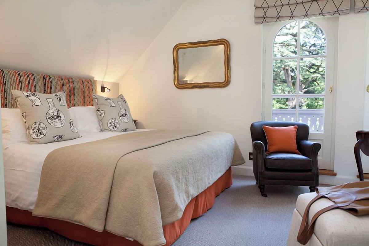 Un dormitorio con cama, una silla, un espejo y una ventana.