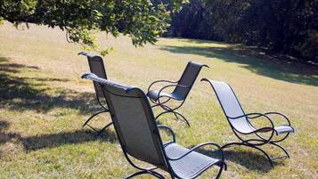 Three outdoor chairs with metal frames and cushioned seats, arranged on a grassy lawn.