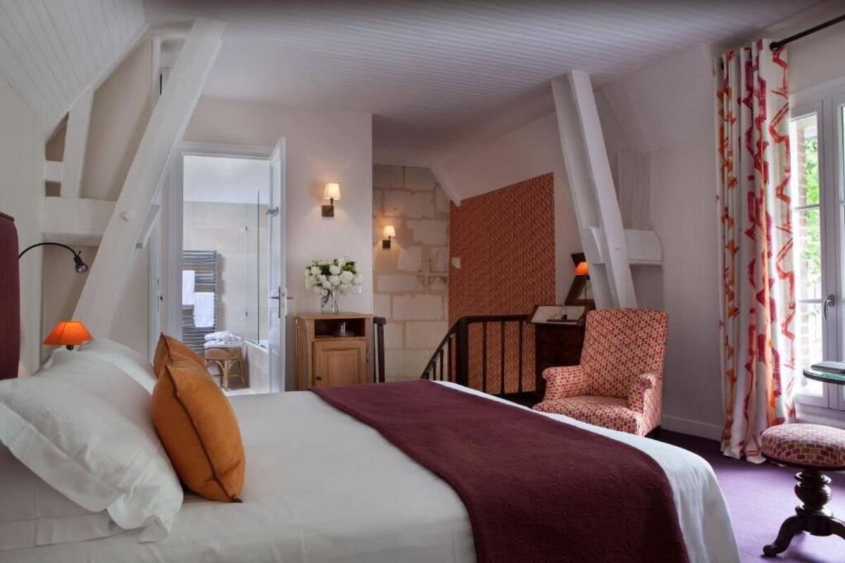 Un dormitorio con una cama, una silla, un escritorio y una escalera.