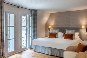 Ein Schlafzimmer mit einem großen Bett, einem Schlafsofa, Blick durch eine Schiebetür und einer Wandlampe.