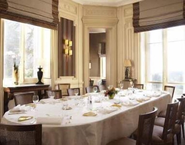 Comedor formal con una larga mesa dispuesta para una comida, sillas elegantes y amplios ventanales que dejan entrar luz natural.