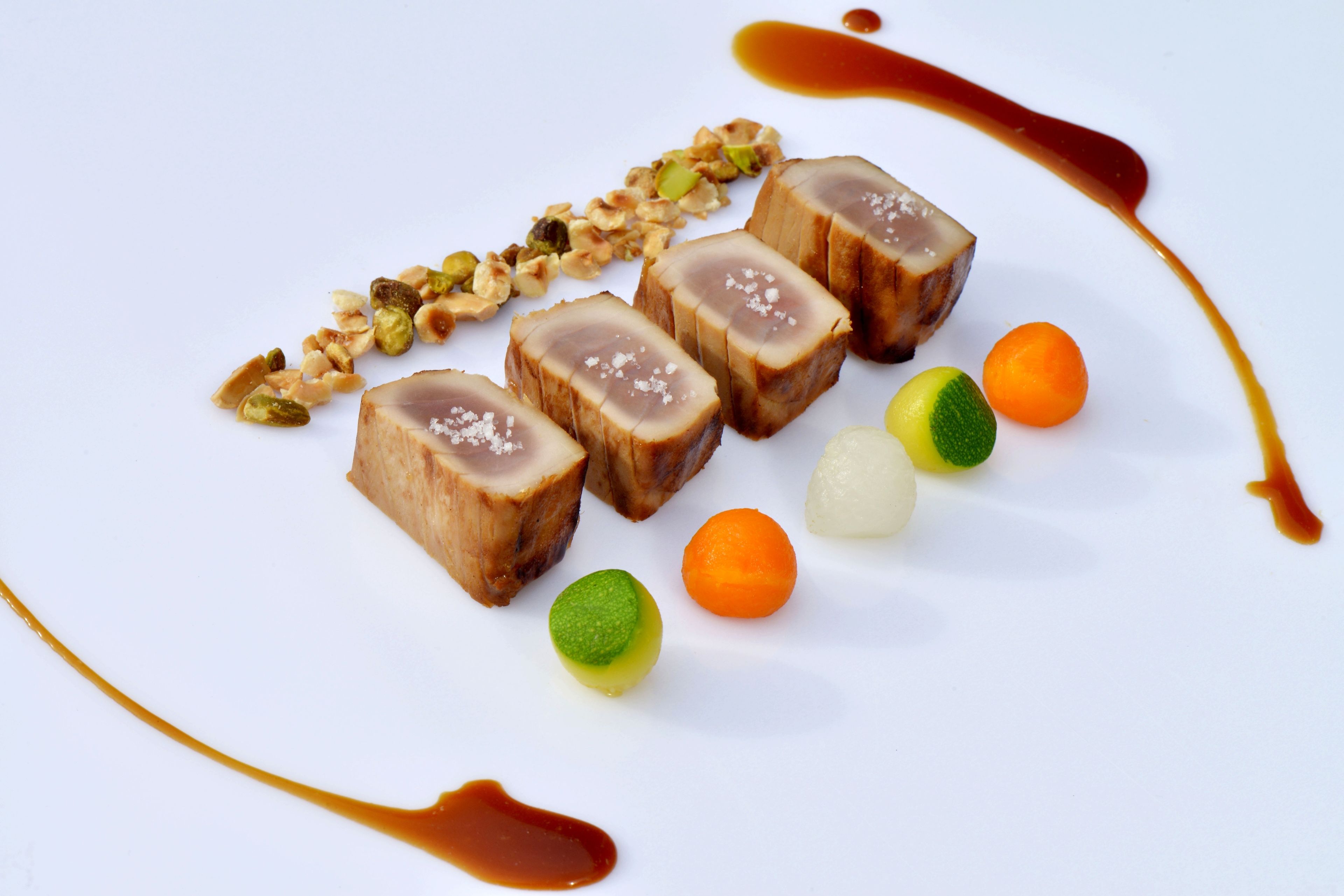 A plate with sliced meat, nuts, and small fruits.