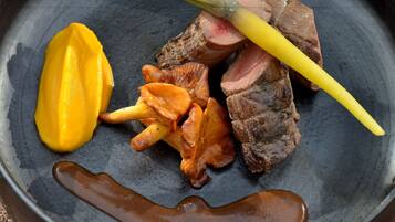 A plate with sliced meat, a yellow vegetable, and a brown sauce.
