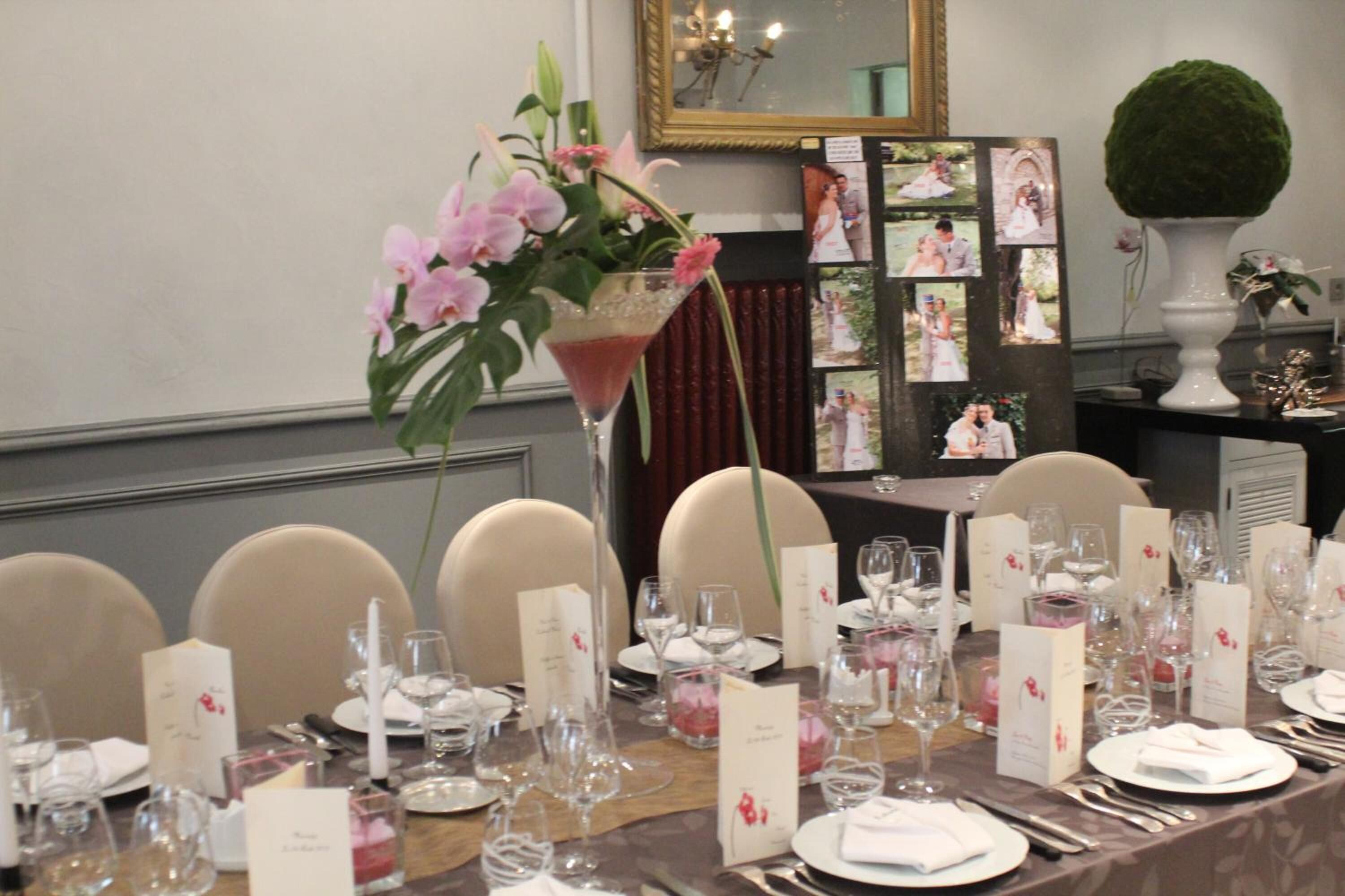Une table à manger élégante, dressée pour un banquet de mariage, agrémentée de centres de table floraux, de marque-places et d’un miroir en arrière-plan.