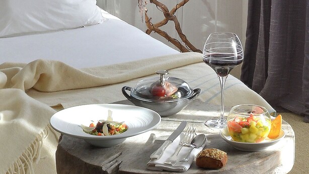 Una mesa de desayuno ordenada con platos de comida, una copa de vino y cubiertos.