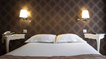 Quarto de hotel com uma cama grande, duas mesinhas de cabeceira, um telefone e duas luminárias de parede.