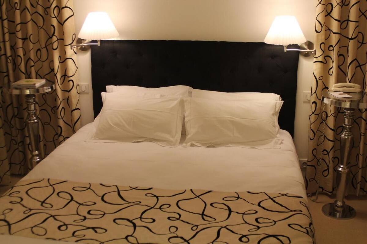 A bed with white linens, a black headboard, and two bedside lamps.
