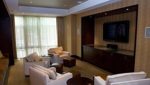 A modern living room with a sofa set, a coffee table, and a flat-screen TV mounted on the wall. - Weichert Suites at Wisconsin Place (Chevy Chase)