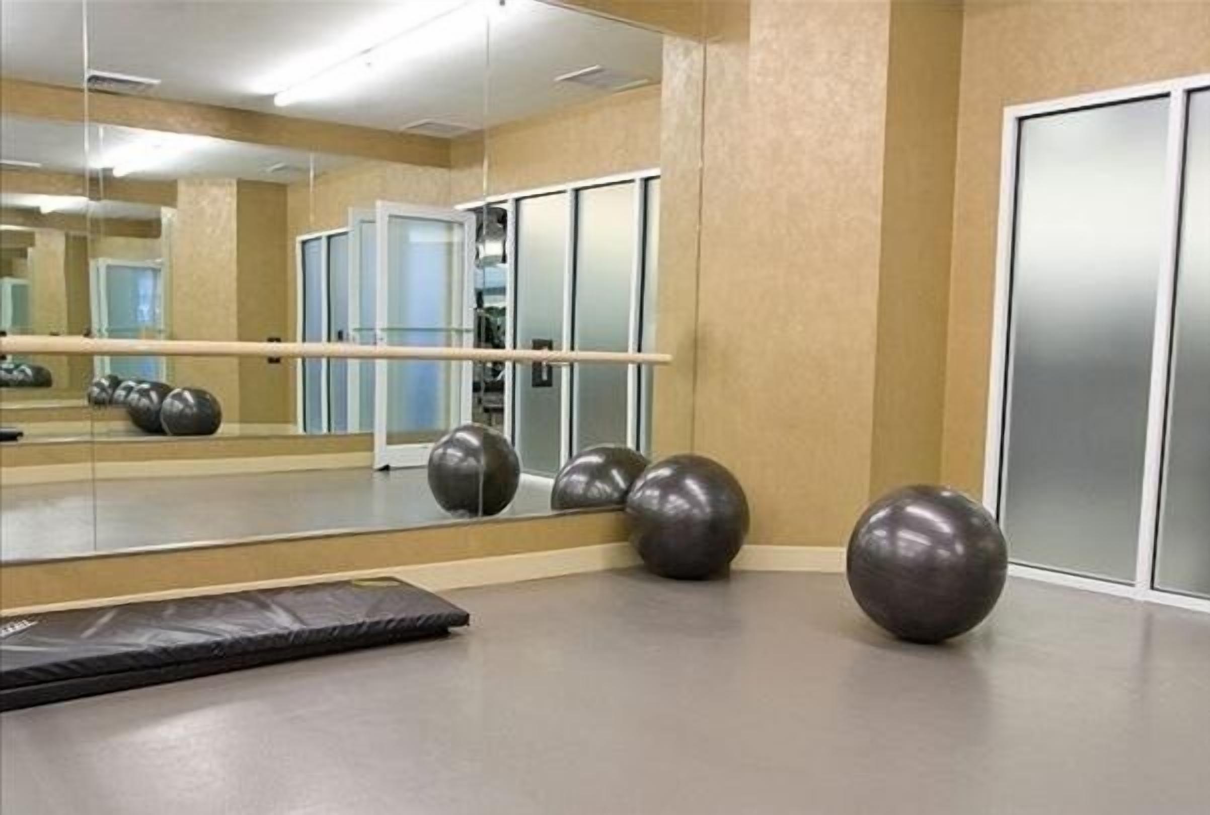A gym with exercise equipment, a mirror, and a padded floor.