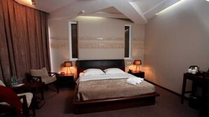 Habitació d'hotel amb llit, dues taules de nit, una cadira i escriptori.