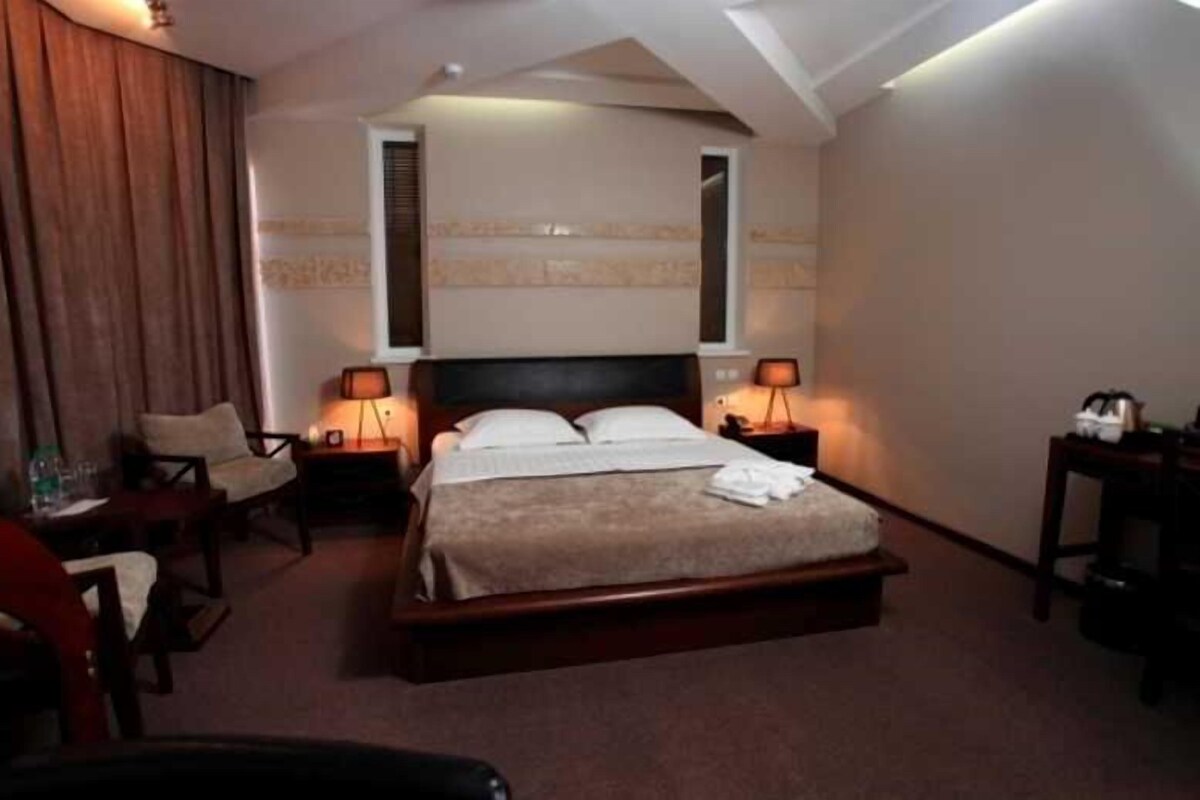 A hotel room with a bed, two bedside tables, a chair, and a desk.