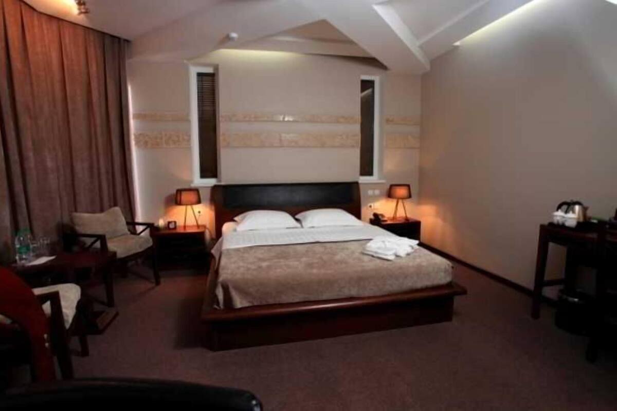 A hotel room with a bed, two bedside tables, a chair, and a desk.