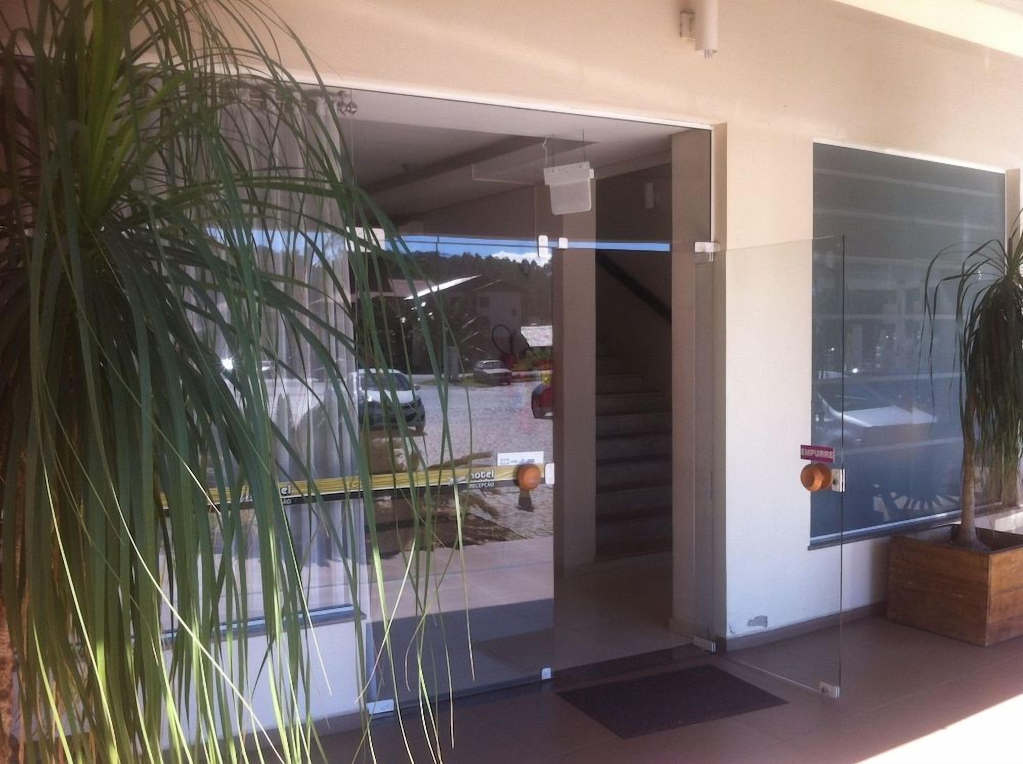 A hotel entrance with a glass door, a staircase, and a potted plant.