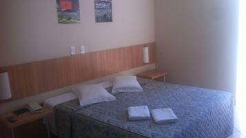 Quarto de hotel com cama, mesas de cabeceira, telefone e obras de arte na parede.
