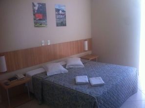 Ein Hotelzimmer mit Bett, Nachttischen, einem Telefon und Bildern an der Wand.