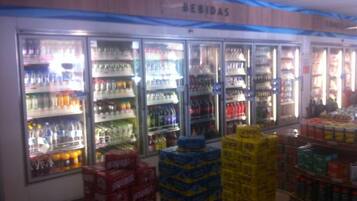 Expositor refrigerado para bebidas com várias prateleiras e pilhas de produtos.