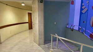A hallway with a marble floor, a handrail, and a blue wall with a geometric design.