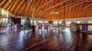 A spacious indoor area with a high wooden ceiling, wooden flooring, and a Christmas tree.