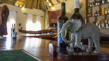 A bar area with a wooden counter, a decorative elephant sculpture, and bottles of wine.