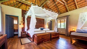 A room with a wooden floor, a bed with a canopy, a nightstand, a door, and a window.