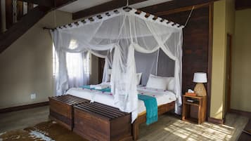 A four-poster canopy bed with a wooden headboard, a small bedside table with a lamp, and a cowhide rug on the floor.