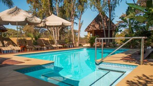 Uma piscina com plataforma de mergulho, espreguiçadeiras e guarda-sóis.