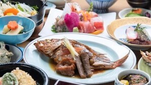 Una variedad de platos, incluyendo un pescado entero, tazones de sopa y otros alimentos, sobre una mesa.