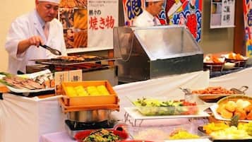 A buffet setup with various food items and a person grilling.