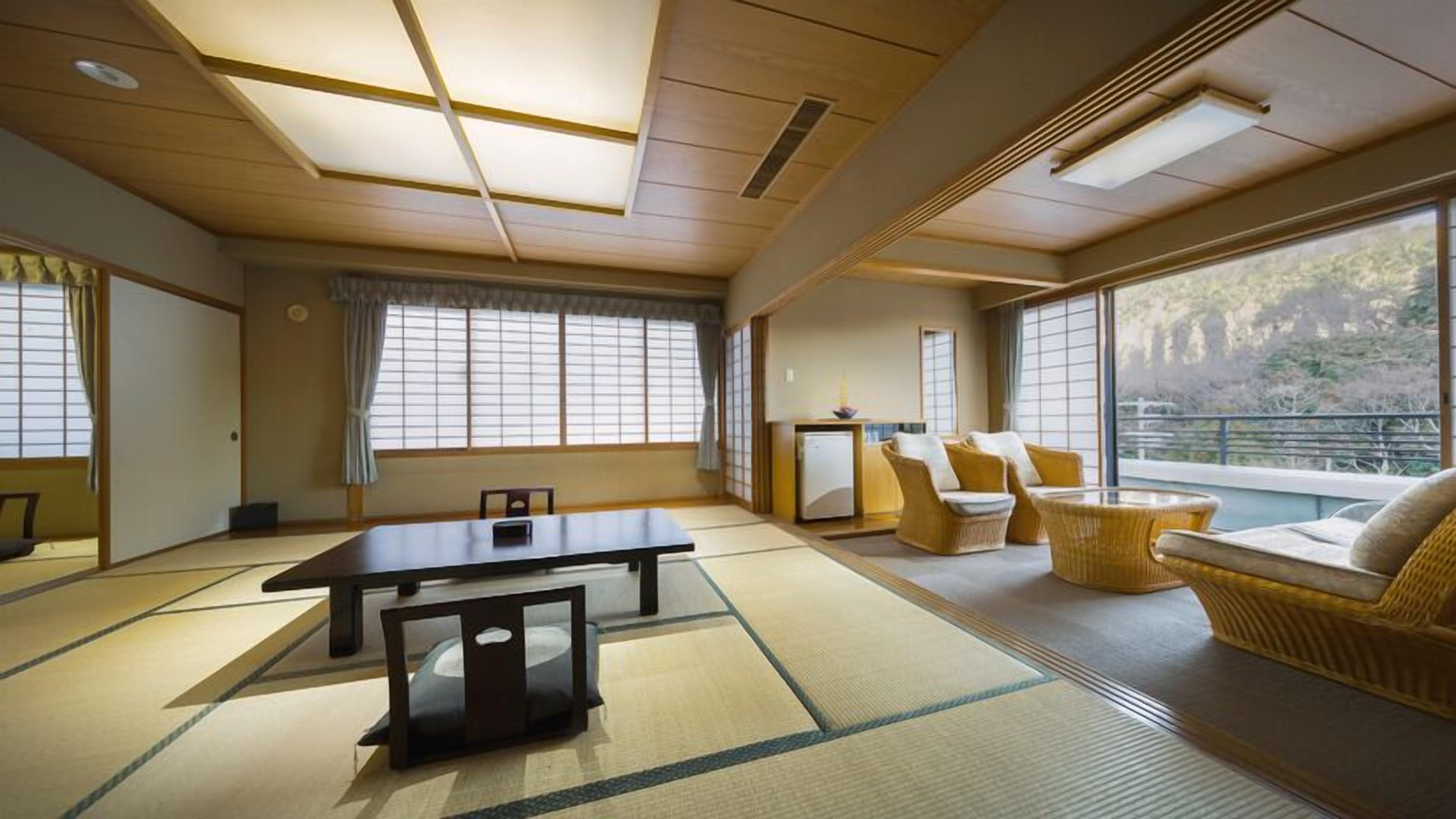 Ein traditioneller japanischer Raum mit Tatami-Bodenbelag, einem niedrigen Tisch und einer Couch mit Kissen.