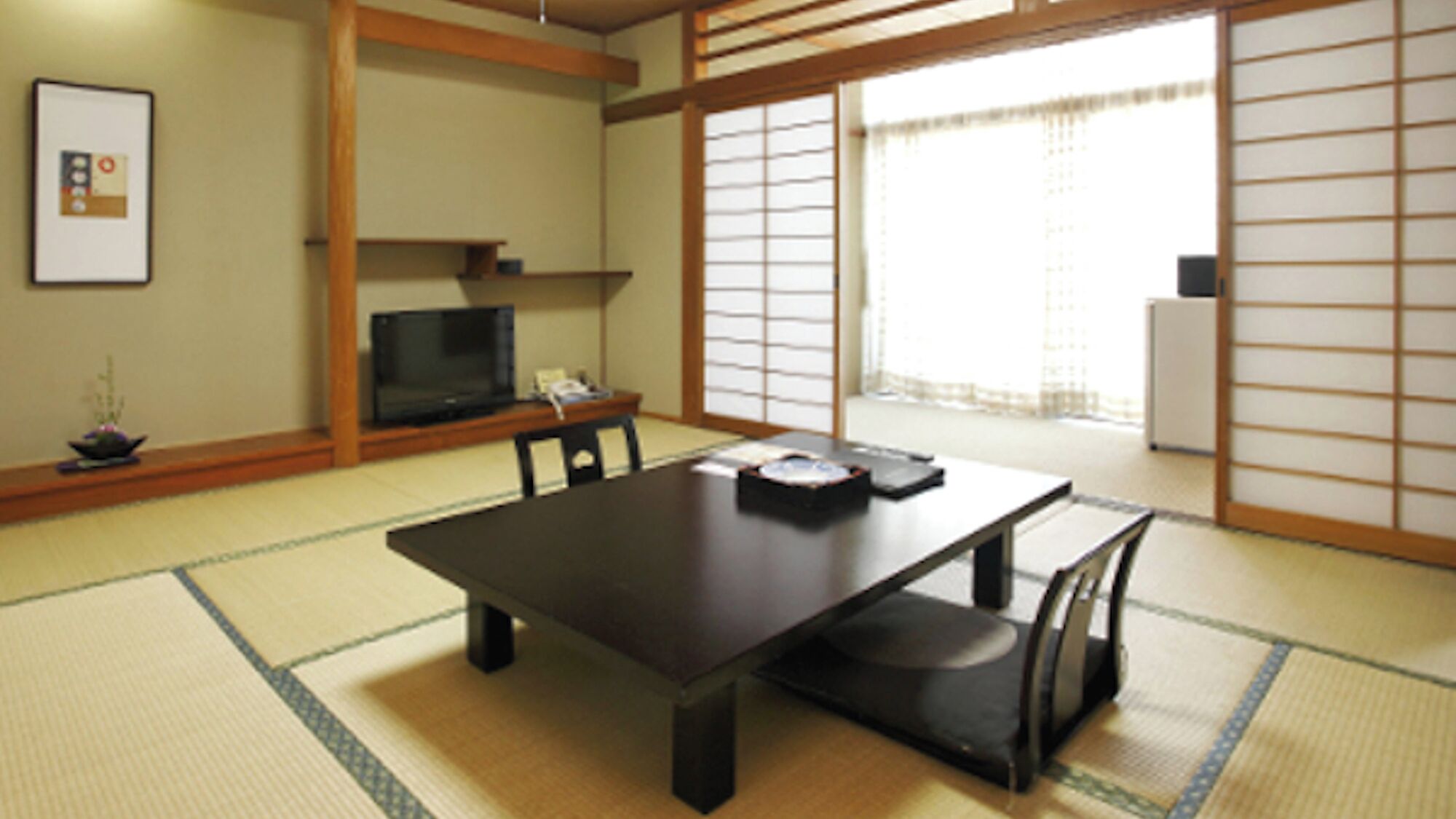 A traditional Japanese room with tatami flooring, a low table, and sliding doors.