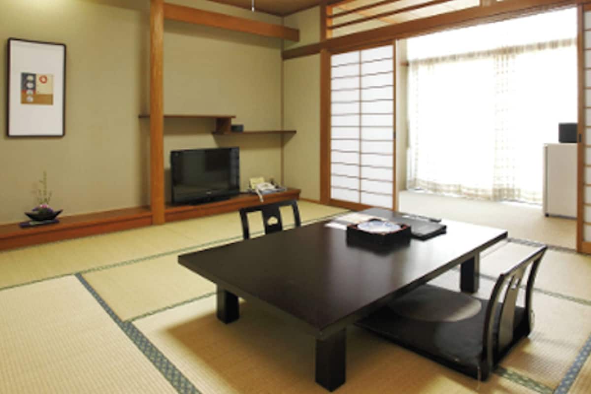 A traditional Japanese room with tatami flooring, a low table, and sliding doors.
