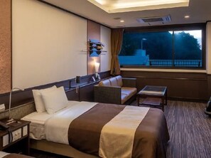 A hotel room with a bed, a seating area, a small table, and a window with a view. - Minamichita Onsenkyo Hananomaru (Minamichita)