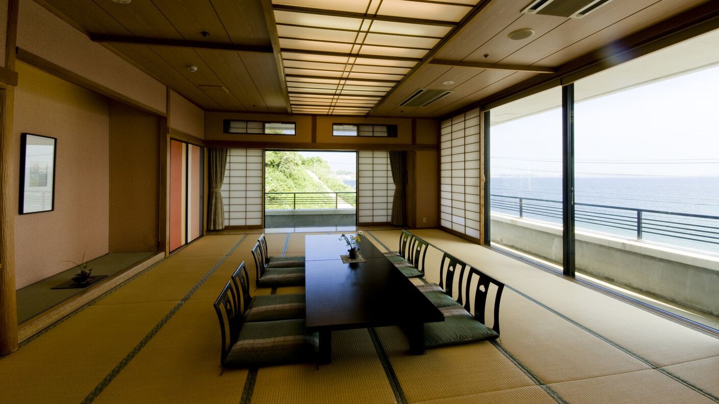 Ein traditioneller japanischer Raum mit Tatami-Böden, einem niedrigen Tisch und gleitenden Schiebetüren.