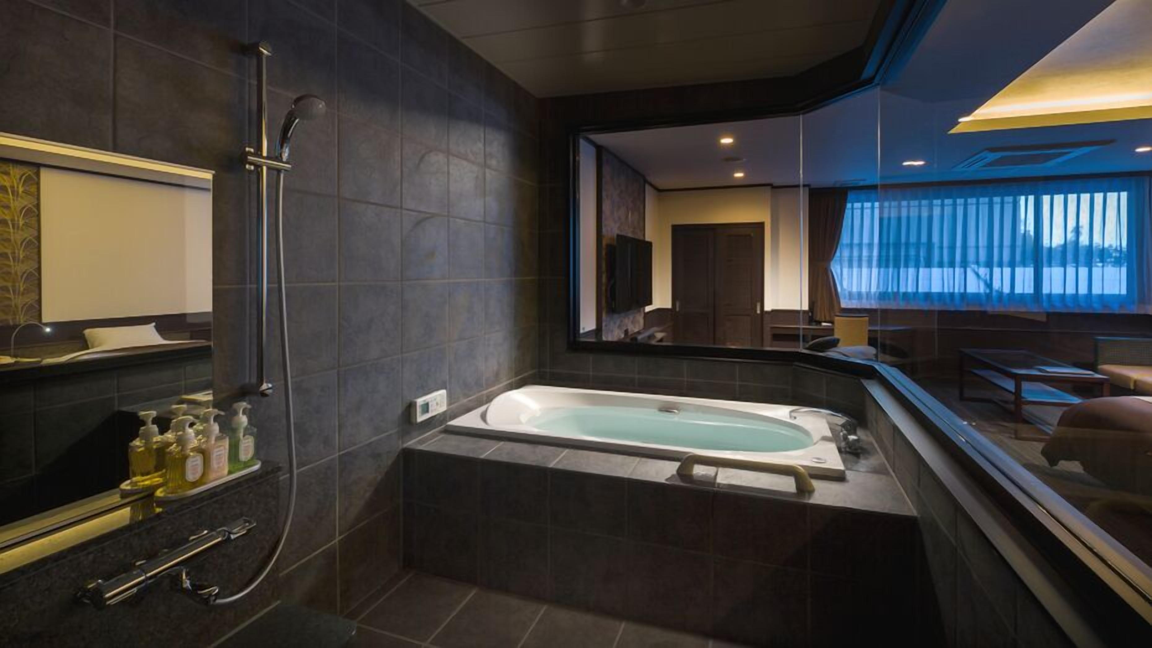 Ein modernes Badezimmer mit einer großen Badewanne, einer Dusche und einem Waschtisch mit Pflegeprodukten.