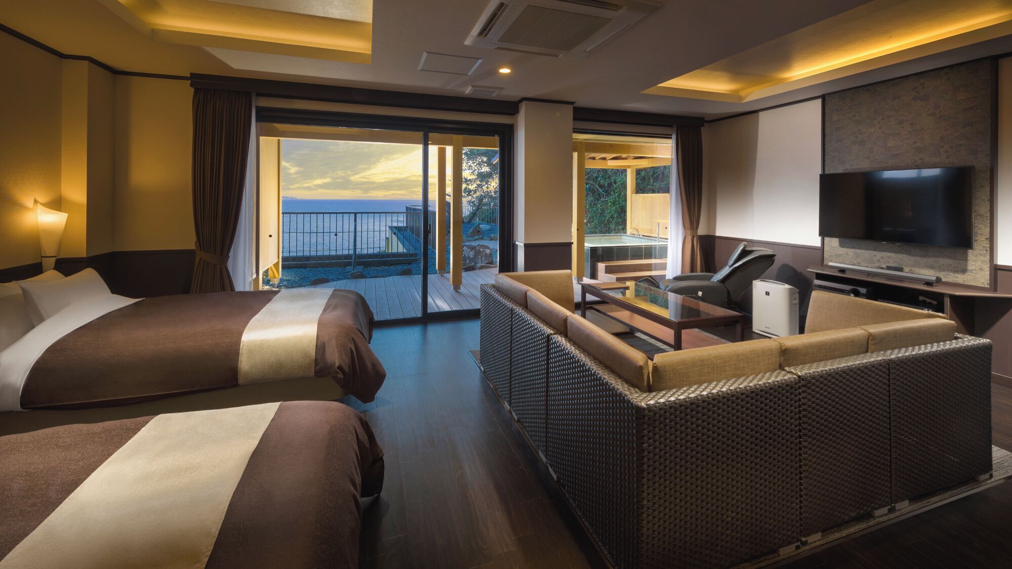 A hotel room with two beds, a sofa, a TV, and a balcony with a view.