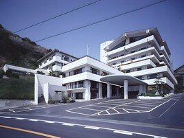 A modern multi-story building with a flat roof and a covered entrance area.
