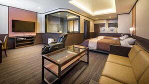 A hotel room with a bed, a sofa, a TV, a massage chair, and a desk. - Minamichita Onsenkyo Hananomaru (Minamichita)