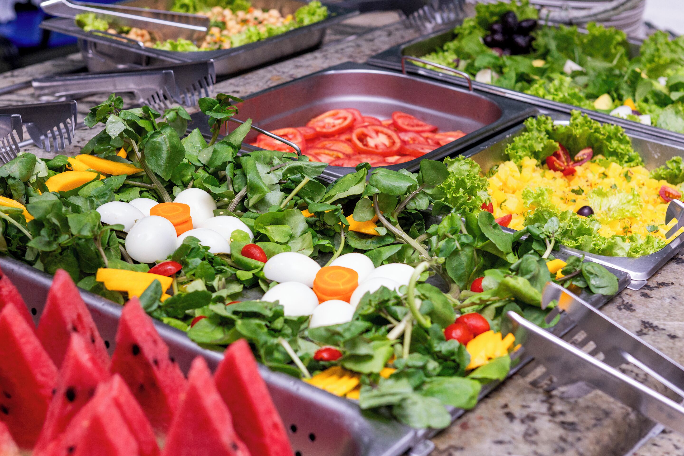 A buffet with various food items including tomatoes, eggs, and leafy greens.