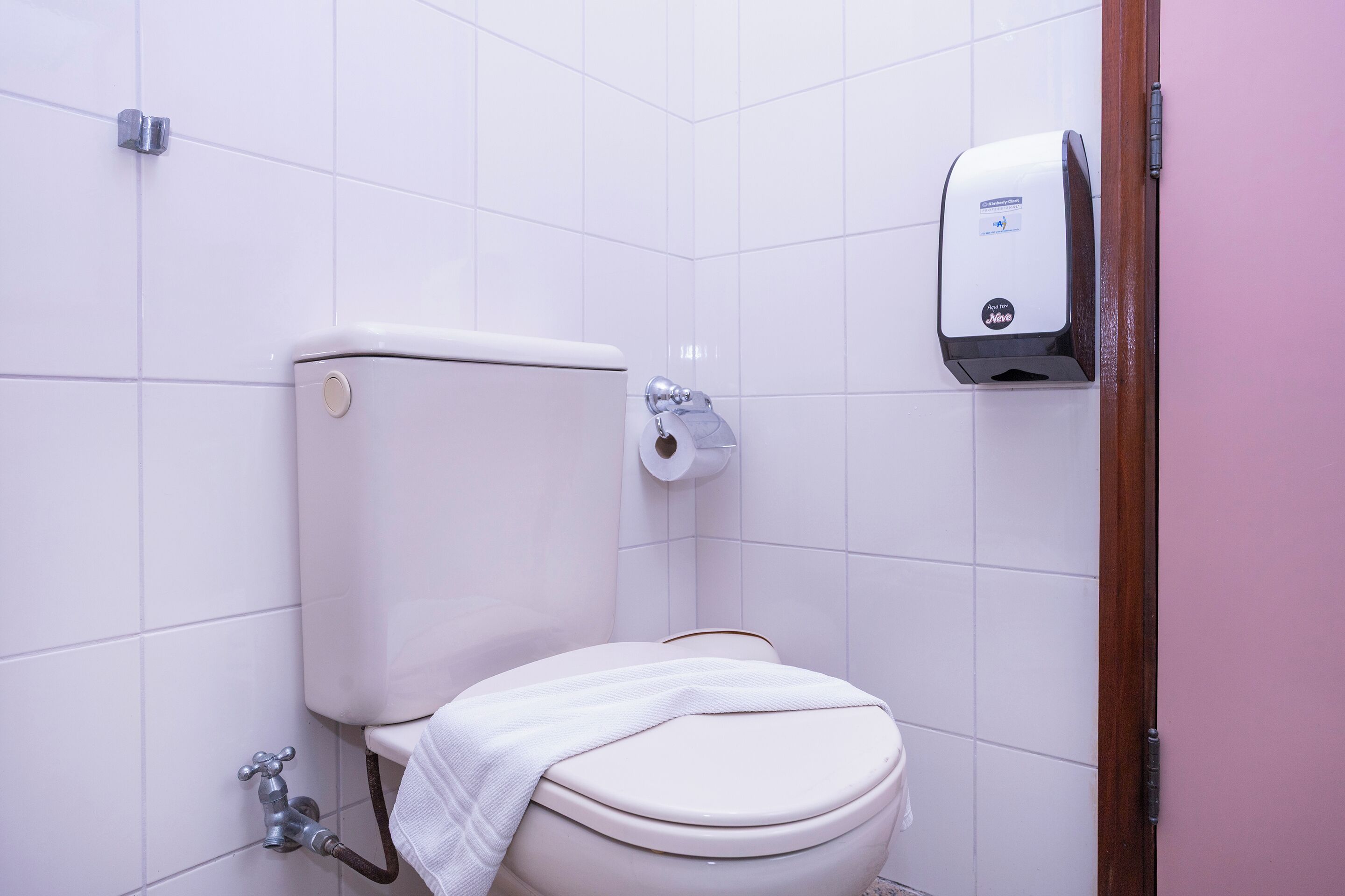 A bathroom with a toilet, a paper towel dispenser, and a hand dryer.
