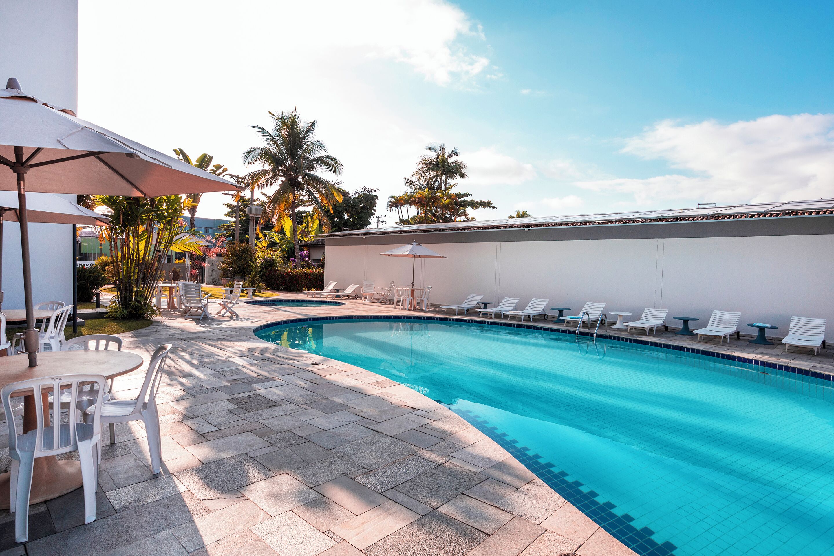Ein Swimmingpool mit Liegestühlen, einem Tisch und Sonnenschirmen.