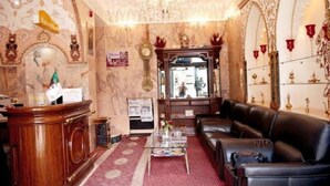 A lobby with a reception desk, a leather sofa, a coffee table, and a chandelier. - Hotel Dar El Aaz (Algiers)