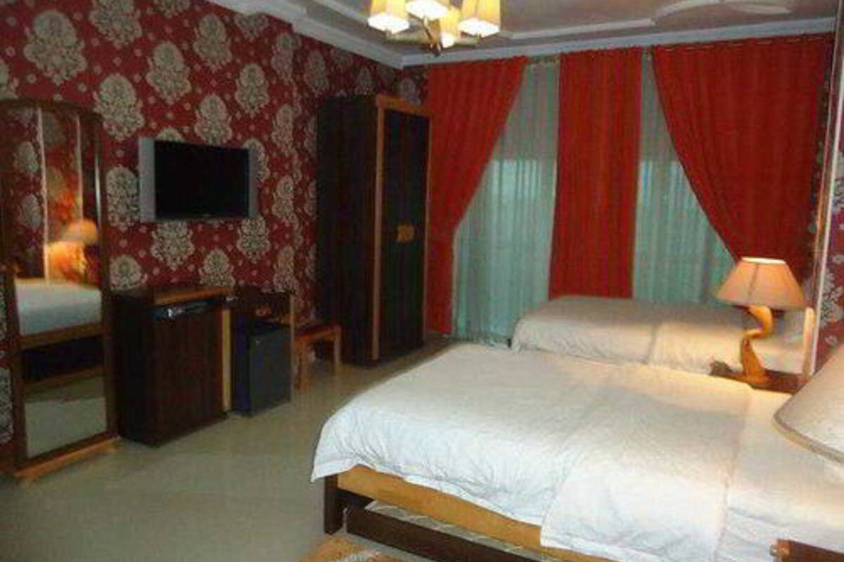 Ein Schlafzimmer mit Doppelbett, Fernseher, Kleiderschrank und Schreibtisch.