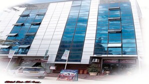 A modern hotel with a glass facade, multiple floors, and a visible restaurant at the ground level. - Hotel Dar El Aaz (Algiers)