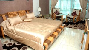 A well-appointed bedroom with a large bed, two armchairs, a small table, and a decorative rug. - Hotel Dar El Aaz (Algiers)