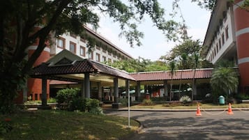 A building with a covered entrance, a paved driveway, and a landscaped garden area.