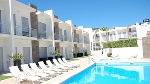 A poolside area with lounge chairs and a swimming pool. - Villas Mare Residence (Nazaré)