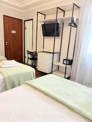 A hotel room with two beds, a desk, a chair, a television, and a small refrigerator. - Hotel Pantanal Vila Mariana (São Paulo)