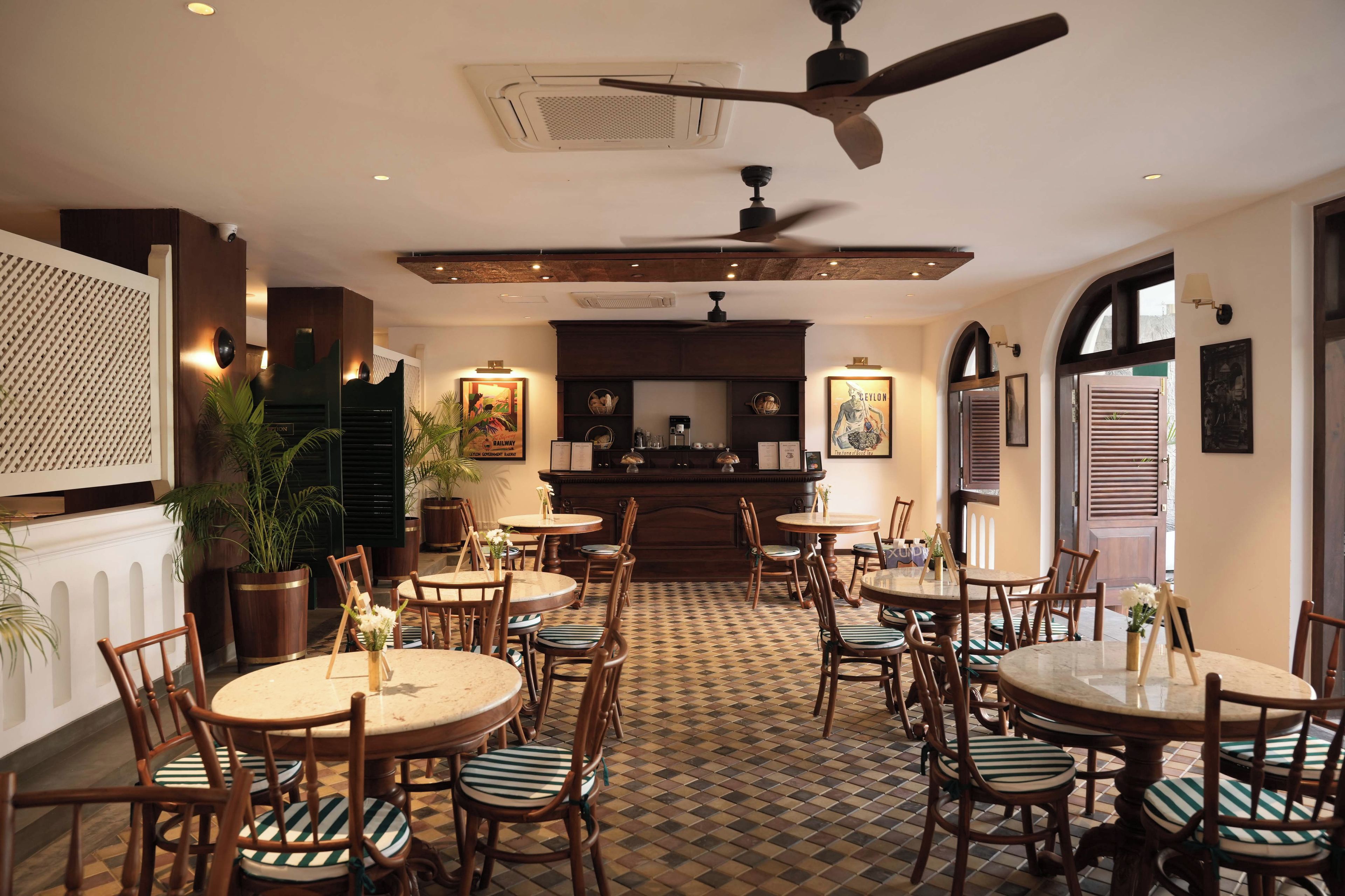 A restaurant interior with multiple round tables and chairs, a ceiling fan, and a patterned floor.